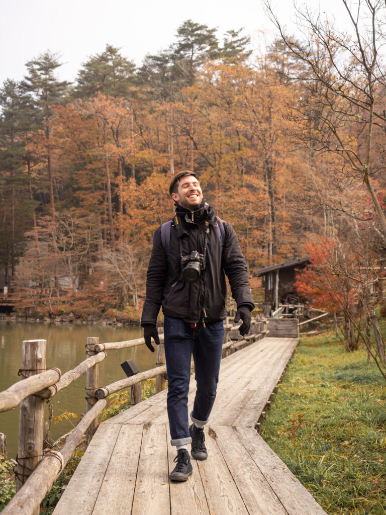 Image of Matt from Keen Physique walking along a board walk in Japan, with autumn leaves in the background.