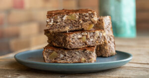 Image of a vegan protein oat & banana slice, with 4 serves loosely stacked on top each other.