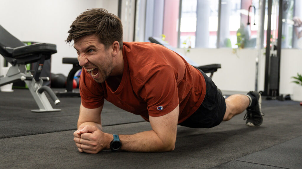 An image of vegan personal trainer Matt pulling a funny face while doing an elbow plank.