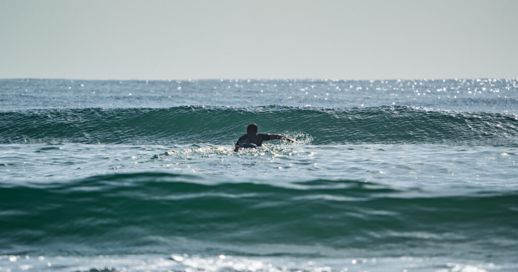 Image of PT Matt surfing at Peregian Beach, paddling out over the waves.