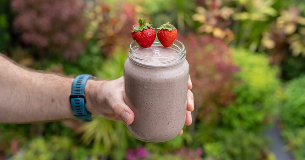 Picture of Matt, a personal trainer, holding his brekky smoothie with a garden in the background.